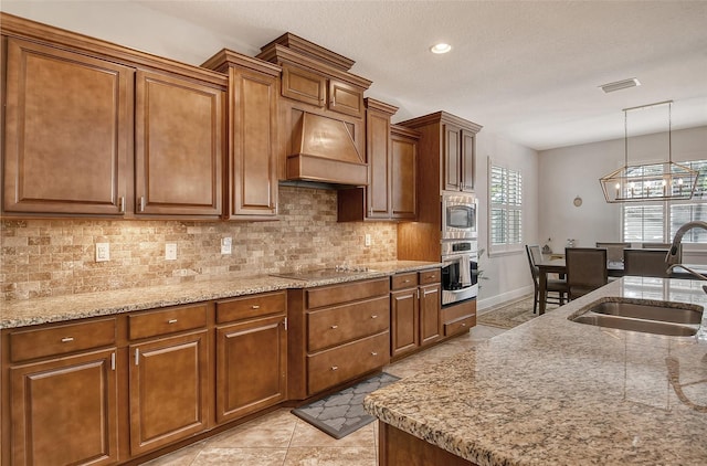 kitchen with premium range hood, sink, hanging light fixtures, stainless steel appliances, and decorative backsplash