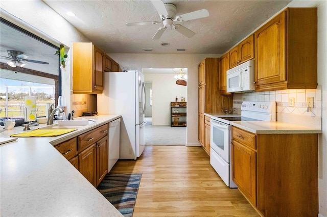 kitchen featuring tasteful backsplash, white appliances, a textured ceiling, light hardwood / wood-style flooring, and sink