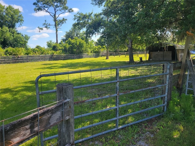 view of gate featuring a rural view and a lawn