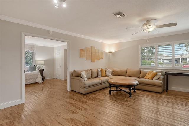 living room featuring ceiling fan, a textured ceiling, crown molding, and light wood-type flooring