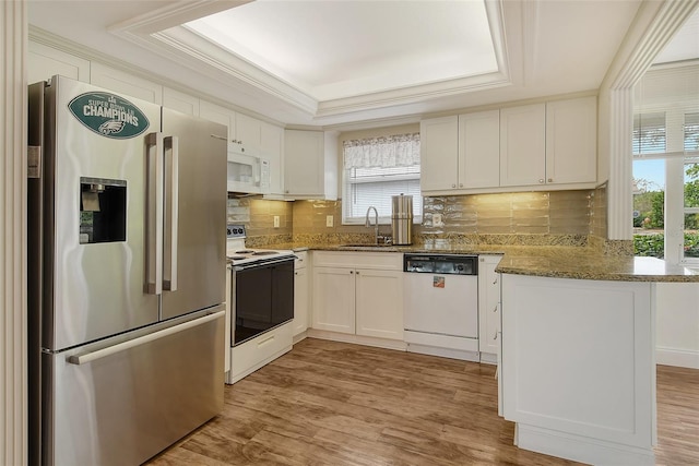 kitchen with white cabinetry, kitchen peninsula, white appliances, light stone counters, and sink