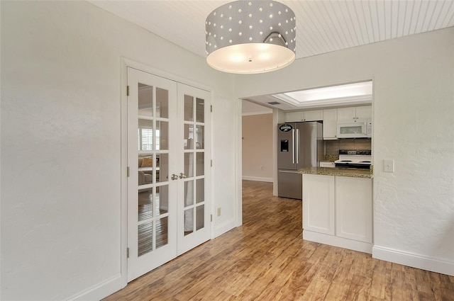 kitchen with electric stove, tasteful backsplash, high end refrigerator, white cabinets, and stone countertops