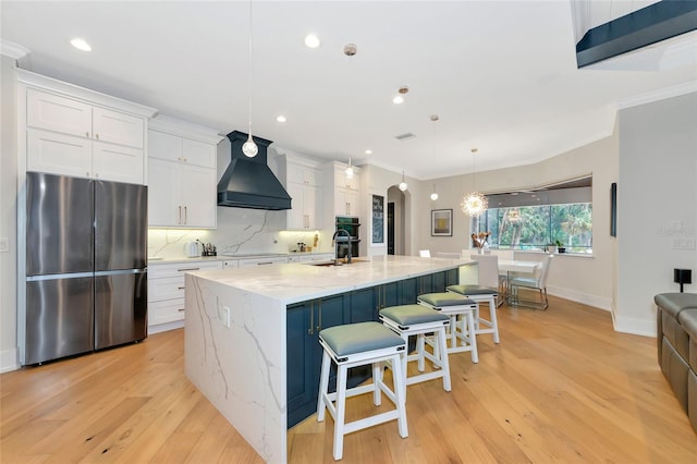 kitchen featuring white cabinetry, pendant lighting, a kitchen island with sink, and black appliances