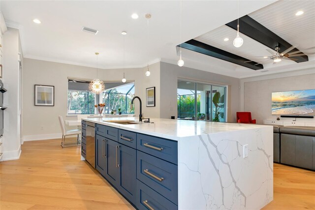 kitchen featuring decorative light fixtures, sink, ceiling fan with notable chandelier, and an island with sink