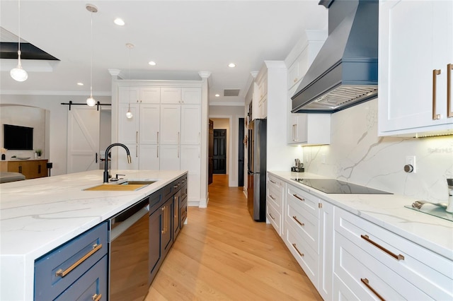 kitchen with a barn door, custom exhaust hood, hanging light fixtures, stainless steel appliances, and white cabinets