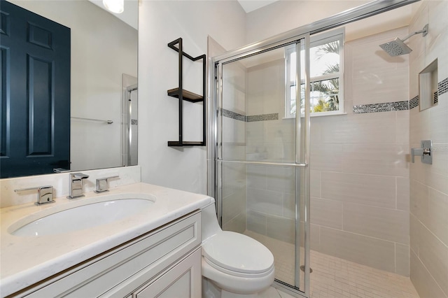 bathroom with toilet, vanity, and a shower with door