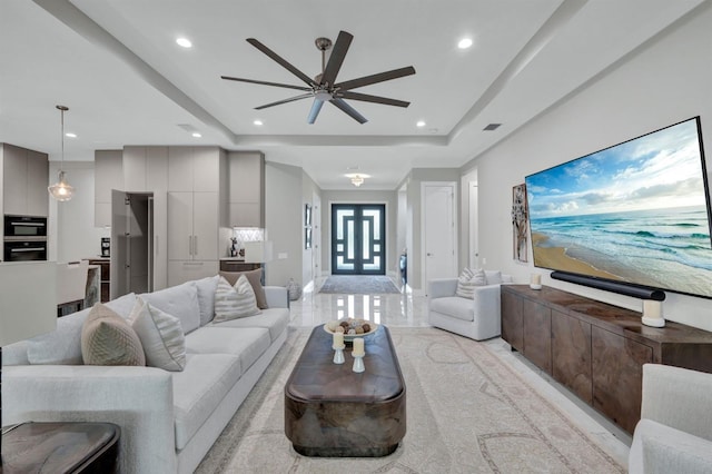 living room featuring ceiling fan and a tray ceiling