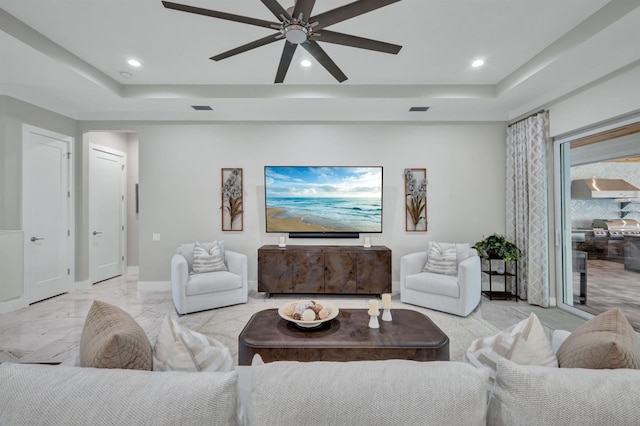 living room with ceiling fan and a raised ceiling