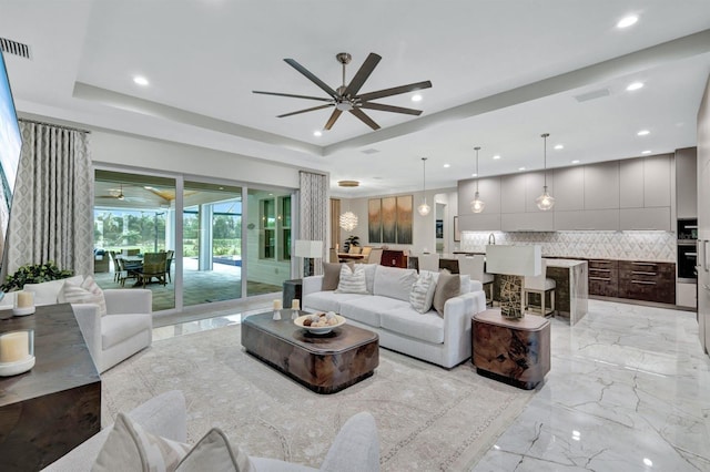 living room with a raised ceiling and ceiling fan