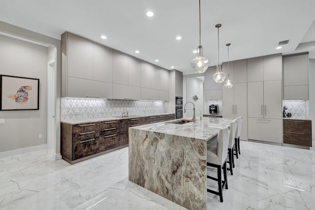 kitchen with hanging light fixtures, decorative backsplash, a kitchen breakfast bar, and a spacious island