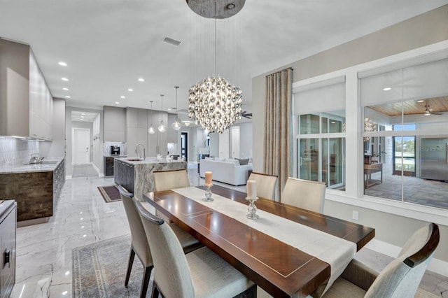 dining space featuring ceiling fan with notable chandelier and sink