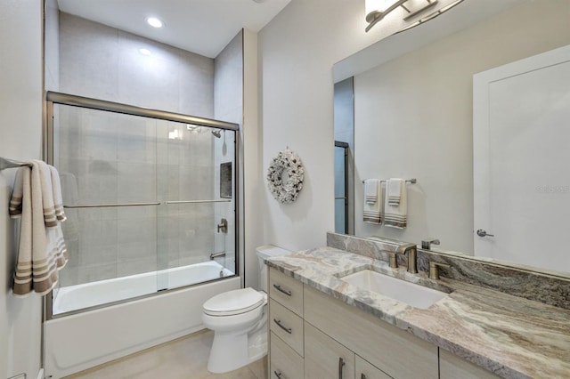 full bathroom with tile patterned floors, bath / shower combo with glass door, toilet, and vanity