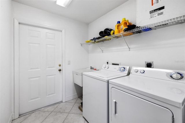 washroom with sink, independent washer and dryer, and light tile patterned flooring