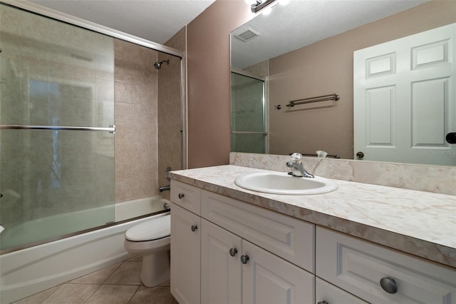 full bathroom featuring toilet, bath / shower combo with glass door, tile patterned flooring, and vanity