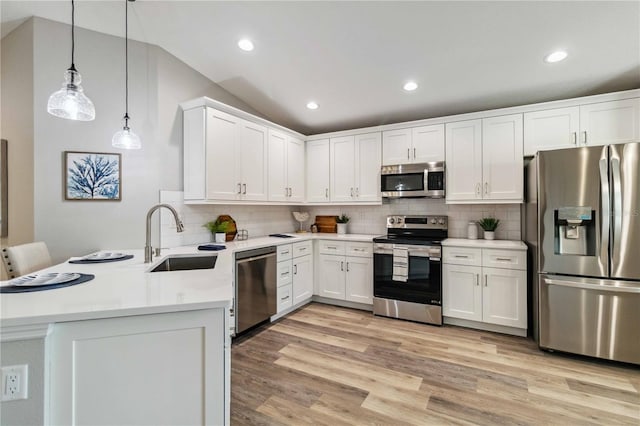 kitchen with vaulted ceiling, kitchen peninsula, sink, hanging light fixtures, and appliances with stainless steel finishes