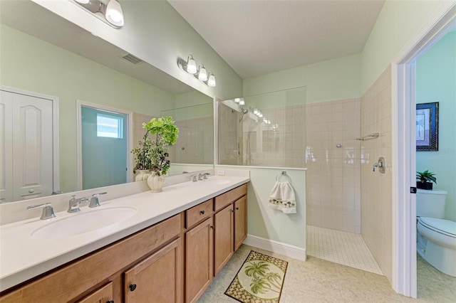 bathroom featuring vanity, toilet, and tiled shower