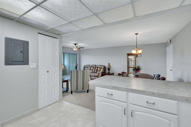 kitchen with ceiling fan with notable chandelier, decorative light fixtures, white cabinetry, a drop ceiling, and electric panel