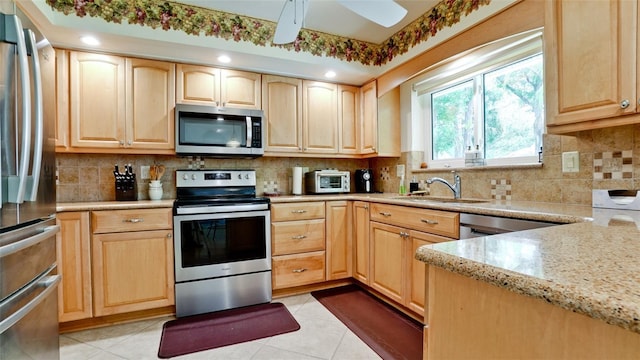 kitchen with light tile patterned floors, light stone counters, light brown cabinets, and stainless steel appliances