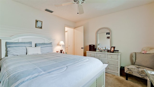 bedroom with ceiling fan, light colored carpet, and a textured ceiling