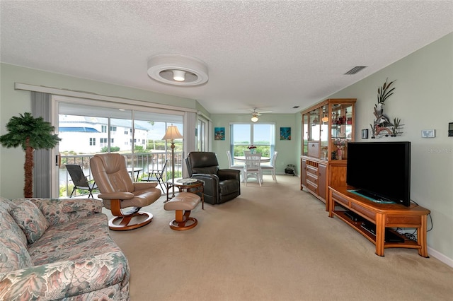 carpeted living room with ceiling fan and a textured ceiling