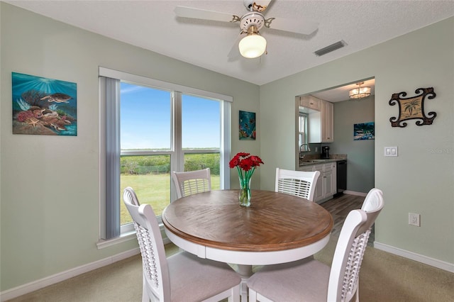 carpeted dining space featuring sink, plenty of natural light, a textured ceiling, and ceiling fan