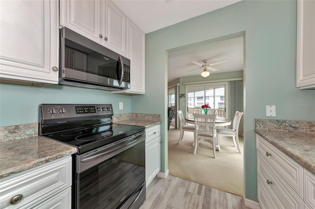 kitchen featuring ceiling fan, white cabinetry, stainless steel appliances, light stone countertops, and light wood-type flooring