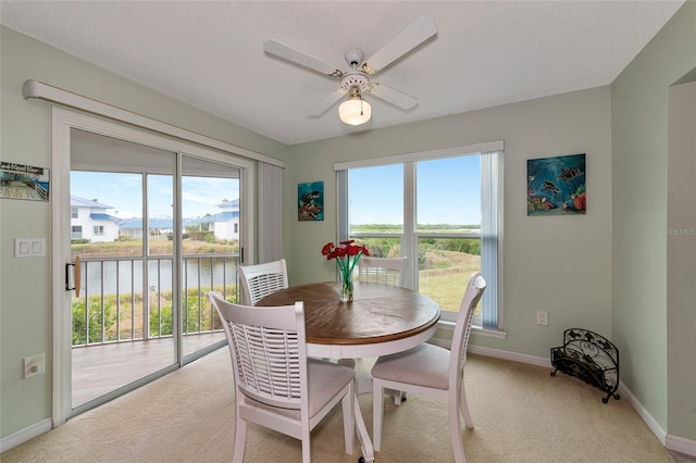 carpeted dining room featuring a water view and ceiling fan