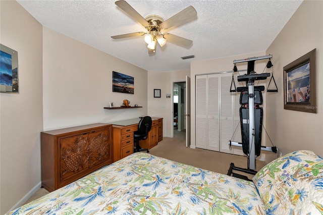 bedroom featuring ceiling fan, light colored carpet, a closet, and a textured ceiling