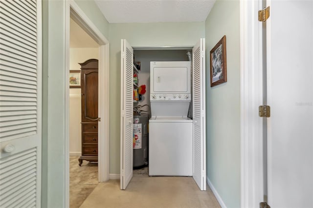 clothes washing area with stacked washer and dryer, water heater, and a textured ceiling