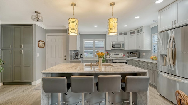 kitchen with decorative light fixtures, light stone counters, stainless steel appliances, and a kitchen island with sink