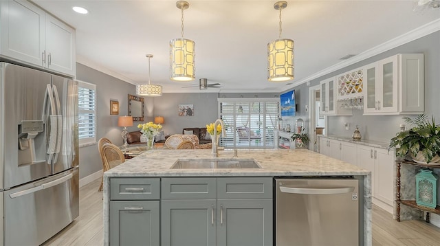 kitchen featuring white cabinets, decorative light fixtures, stainless steel appliances, an island with sink, and sink