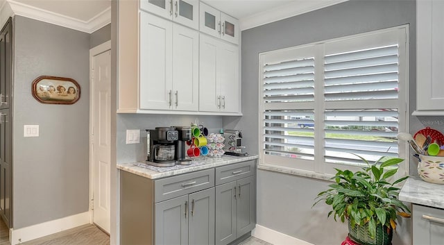 kitchen featuring white cabinetry, ornamental molding, and light stone countertops