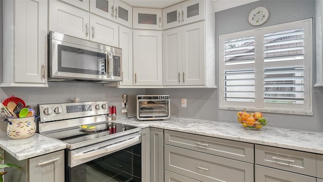 kitchen with light stone counters, white cabinetry, and stainless steel appliances