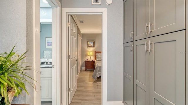 hall with crown molding, sink, and light wood-type flooring