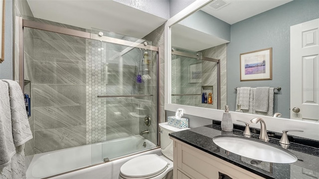 full bathroom featuring bath / shower combo with glass door, toilet, and vanity