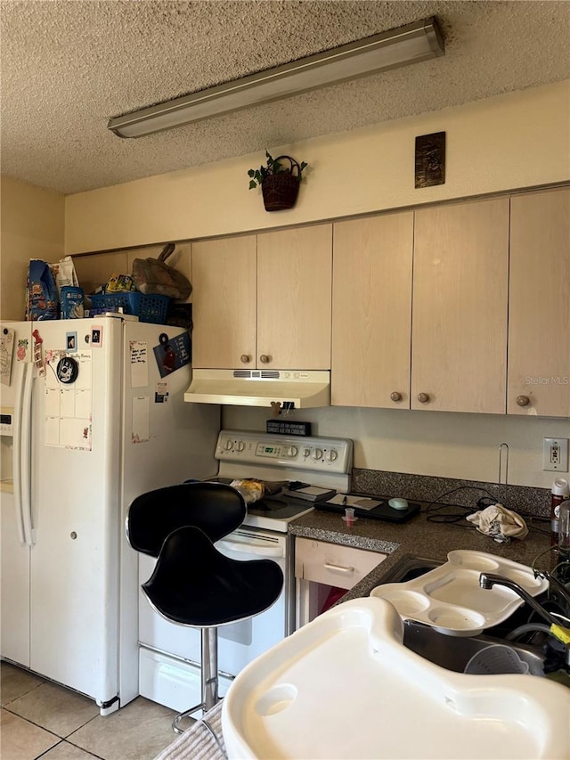 kitchen with white appliances, a textured ceiling, and light tile patterned flooring