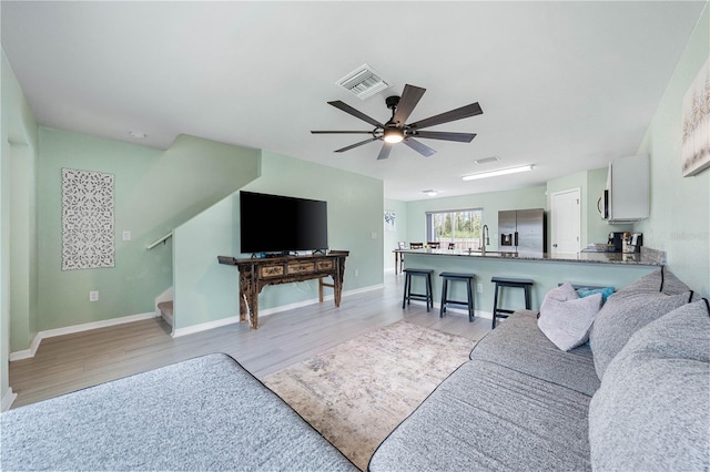 living room featuring ceiling fan, sink, and light hardwood / wood-style flooring