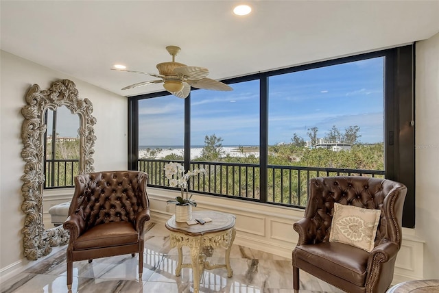 sitting room with a ceiling fan, recessed lighting, and a decorative wall