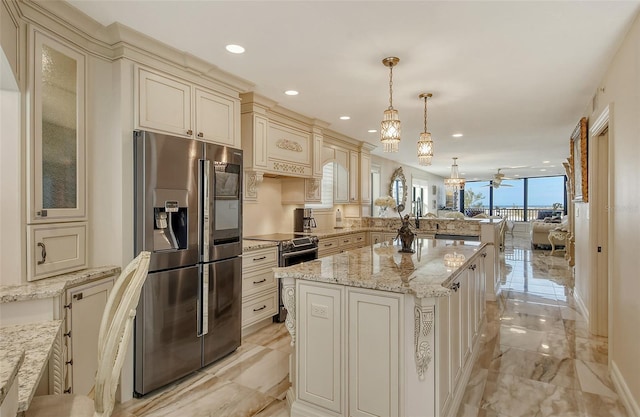 kitchen with cream cabinets, a peninsula, marble finish floor, appliances with stainless steel finishes, and glass insert cabinets