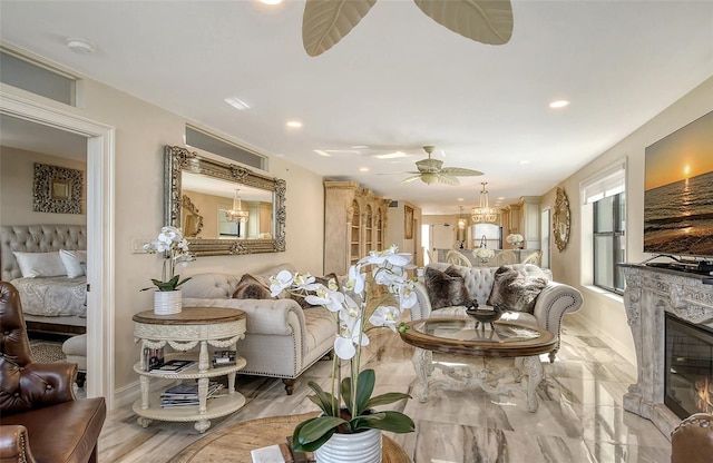 living room featuring a glass covered fireplace, recessed lighting, baseboards, and ceiling fan with notable chandelier