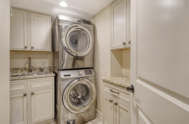 laundry room featuring stacked washer and dryer, a sink, and cabinet space