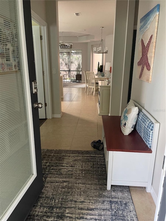 hallway with a chandelier and dark tile patterned floors