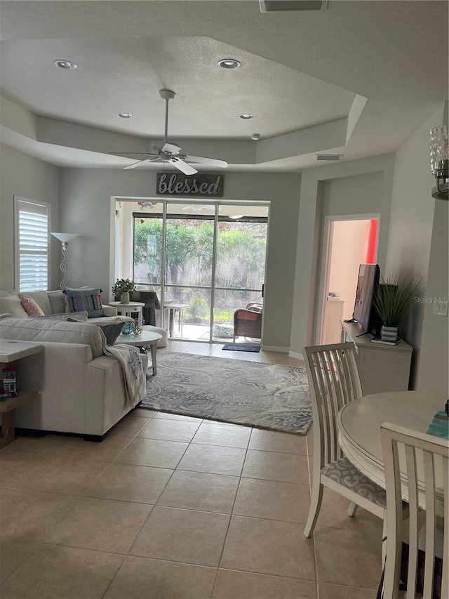 living room featuring ceiling fan, a healthy amount of sunlight, light tile patterned floors, and a tray ceiling