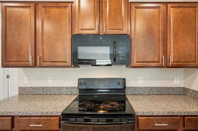 kitchen featuring light stone counters and black appliances