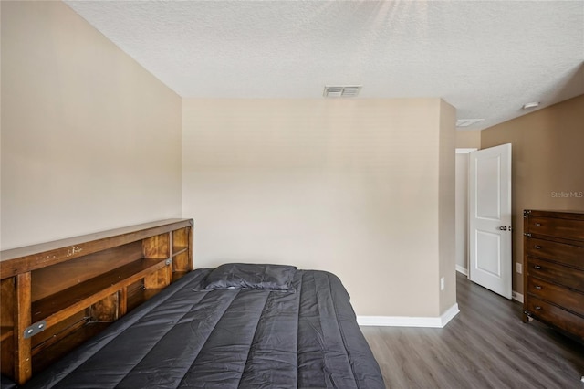 bedroom with dark hardwood / wood-style floors and a textured ceiling