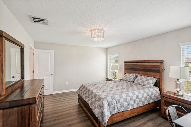 bedroom featuring a textured ceiling, dark hardwood / wood-style floors, and a notable chandelier