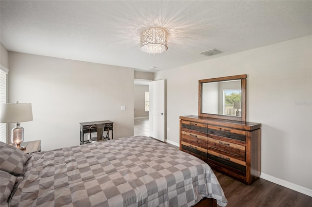 bedroom featuring a textured ceiling, dark hardwood / wood-style floors, and an inviting chandelier