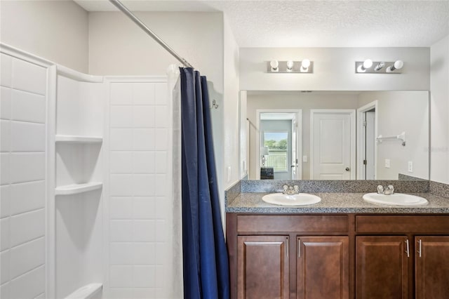 bathroom with a textured ceiling, vanity, and curtained shower