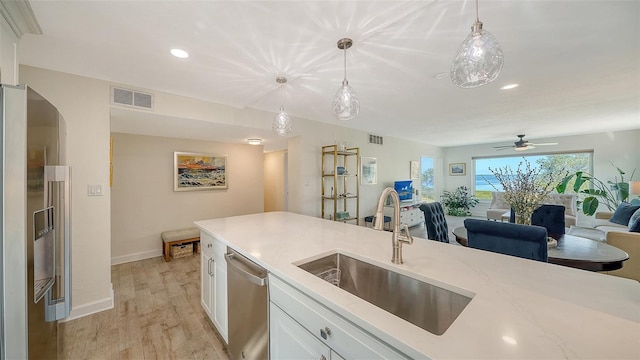 kitchen with appliances with stainless steel finishes, sink, pendant lighting, and white cabinets