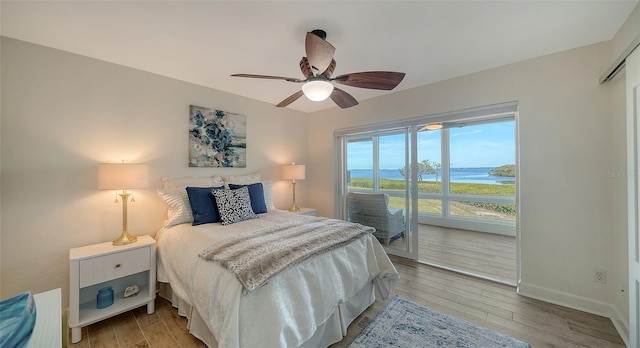 bedroom featuring a water view, ceiling fan, access to exterior, and hardwood / wood-style floors